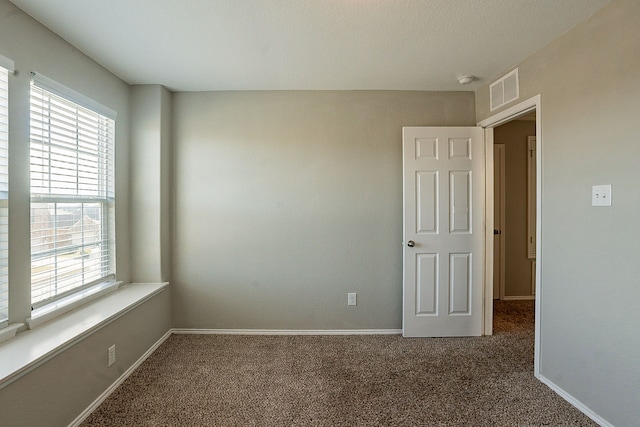 carpeted spare room featuring a healthy amount of sunlight