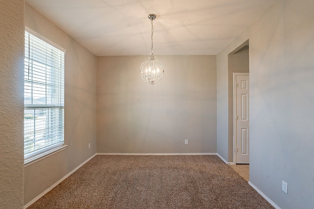 unfurnished room featuring an inviting chandelier and light colored carpet