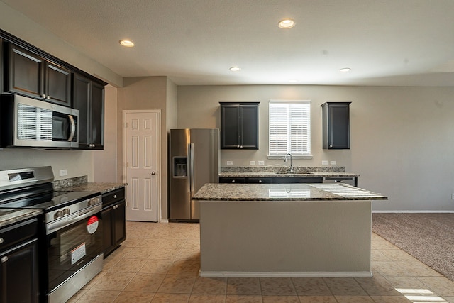 kitchen featuring light tile patterned flooring, sink, a kitchen island, stainless steel appliances, and light stone countertops