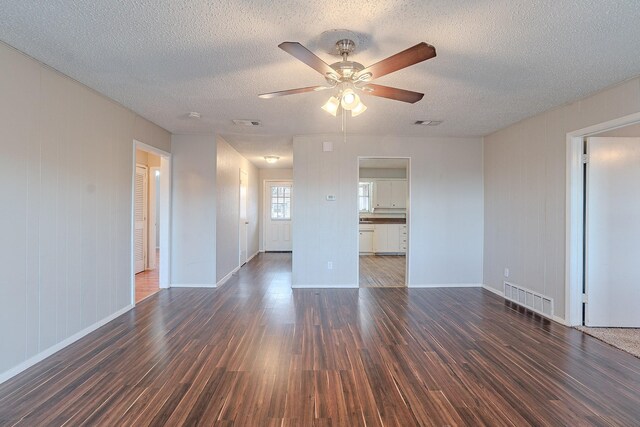 empty room featuring a textured ceiling, ceiling fan, and dark hardwood / wood-style flooring