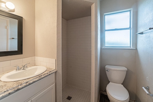 bathroom featuring toilet, vanity, and a tile shower