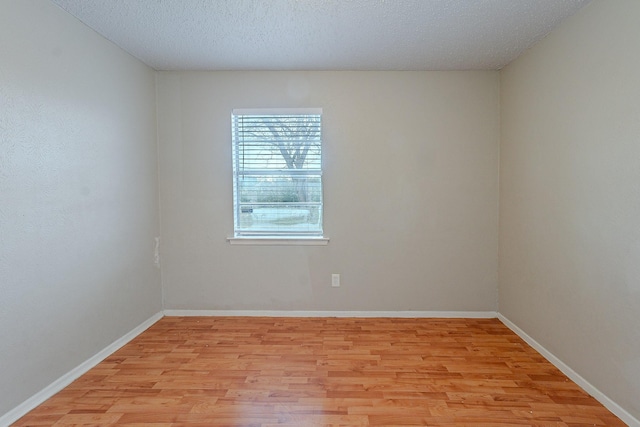 empty room featuring a textured ceiling and light hardwood / wood-style flooring