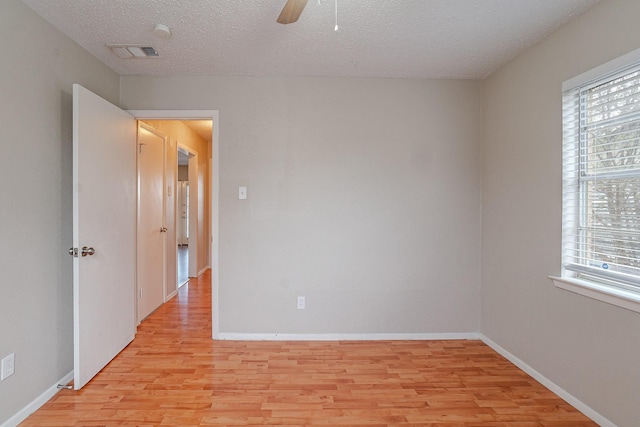 spare room featuring ceiling fan, a textured ceiling, light hardwood / wood-style flooring, and a wealth of natural light