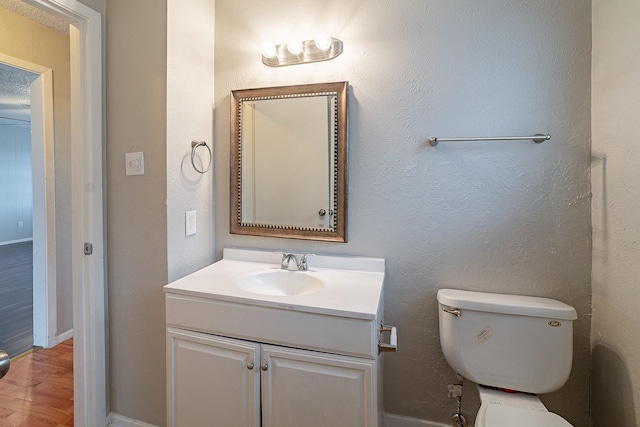 bathroom with toilet, vanity, and hardwood / wood-style flooring