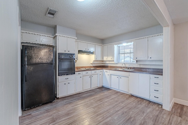 kitchen featuring a textured ceiling, white cabinets, black appliances, sink, and light wood-type flooring