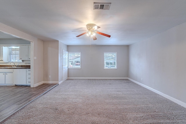 unfurnished room featuring ceiling fan, light colored carpet, and sink