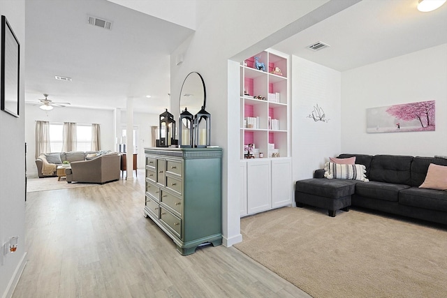 living room with ceiling fan, built in shelves, and light hardwood / wood-style flooring