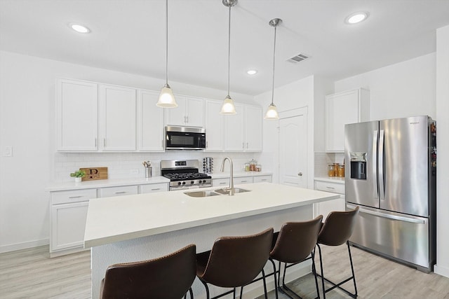 kitchen with white cabinetry, sink, decorative light fixtures, and appliances with stainless steel finishes