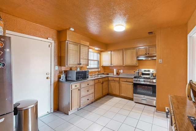 kitchen with stainless steel gas stove, light tile patterned floors, a textured ceiling, and sink