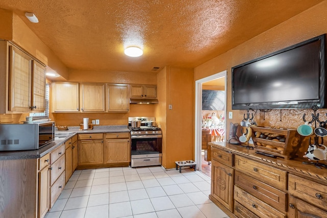 kitchen featuring gas stove, light tile patterned flooring, and a textured ceiling