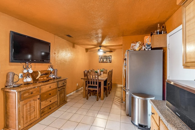 dining space featuring ceiling fan, light tile patterned floors, and a textured ceiling