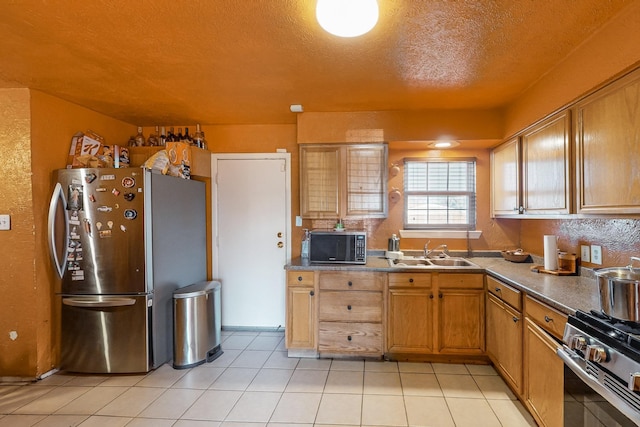 kitchen featuring sink, light tile patterned flooring, stainless steel appliances, and a textured ceiling