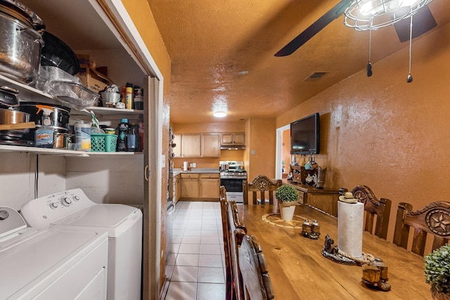 laundry area featuring light tile patterned floors, a textured ceiling, washer and clothes dryer, and ceiling fan