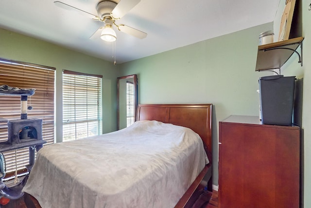 bedroom featuring a wood stove and ceiling fan