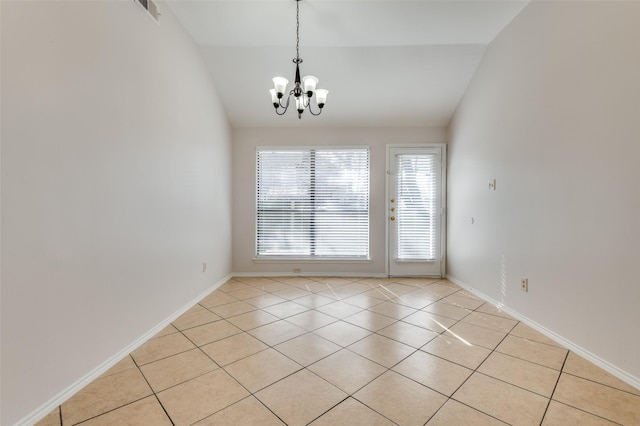 tiled spare room featuring lofted ceiling and a chandelier