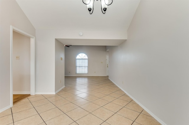 unfurnished room with lofted ceiling, an inviting chandelier, and light tile patterned floors