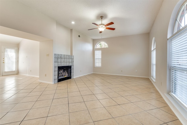 unfurnished living room featuring a tile fireplace, ceiling fan, and light tile patterned floors