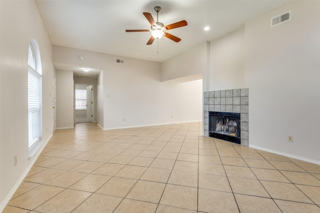 unfurnished living room featuring a tiled fireplace, ceiling fan, and light tile patterned floors