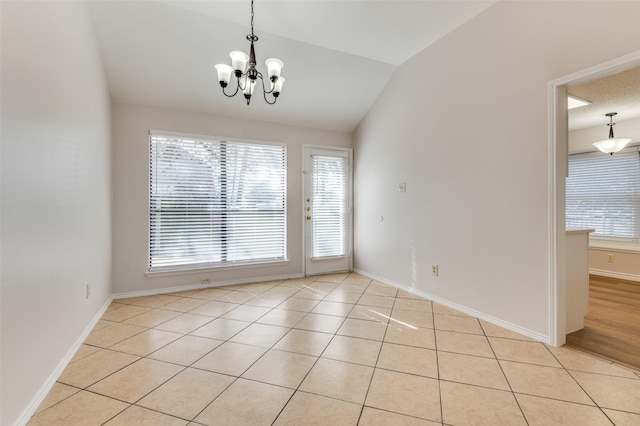 tiled empty room with lofted ceiling, an inviting chandelier, and plenty of natural light