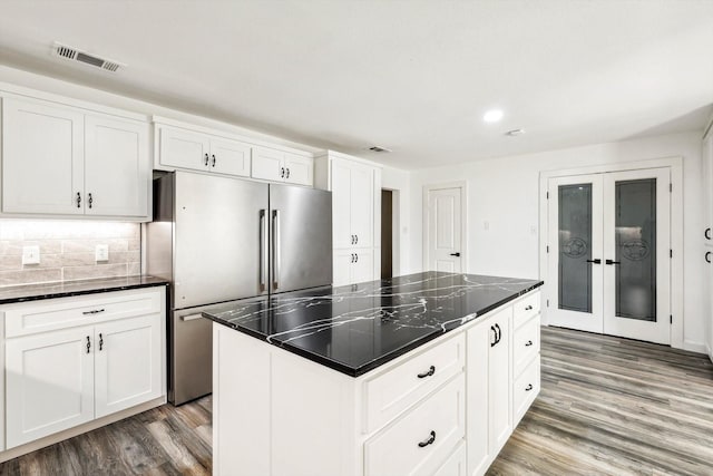 kitchen with backsplash, high quality fridge, white cabinetry, and a center island