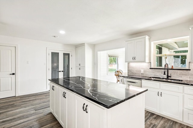 kitchen with decorative backsplash, dark hardwood / wood-style flooring, a kitchen island, sink, and white cabinetry