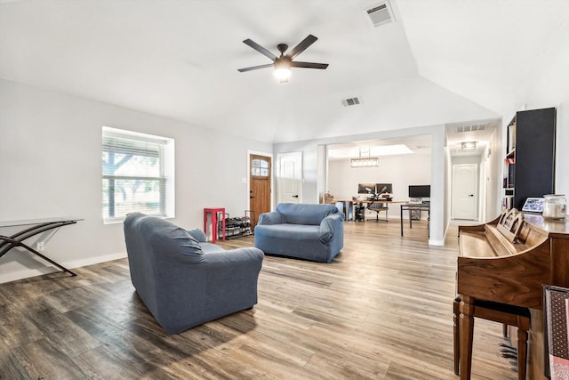 living room featuring hardwood / wood-style flooring, ceiling fan with notable chandelier, and vaulted ceiling