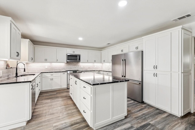 kitchen featuring hardwood / wood-style floors, sink, a kitchen island, white cabinetry, and stainless steel appliances