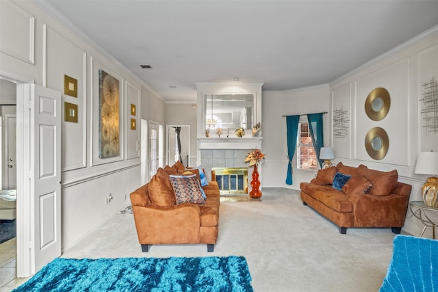 living room with a tiled fireplace, ornamental molding, and carpet floors