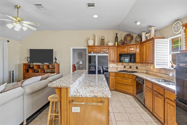 kitchen with vaulted ceiling, black appliances, a breakfast bar, and a kitchen island