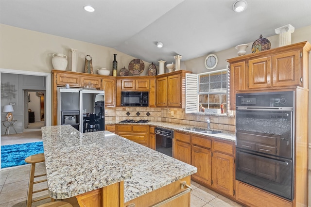 kitchen featuring sink, a breakfast bar area, backsplash, a center island, and black appliances