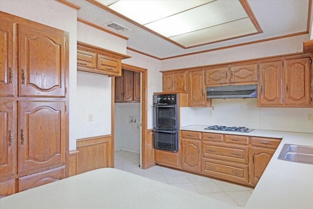 kitchen with sink, gas cooktop, double oven, crown molding, and wood walls