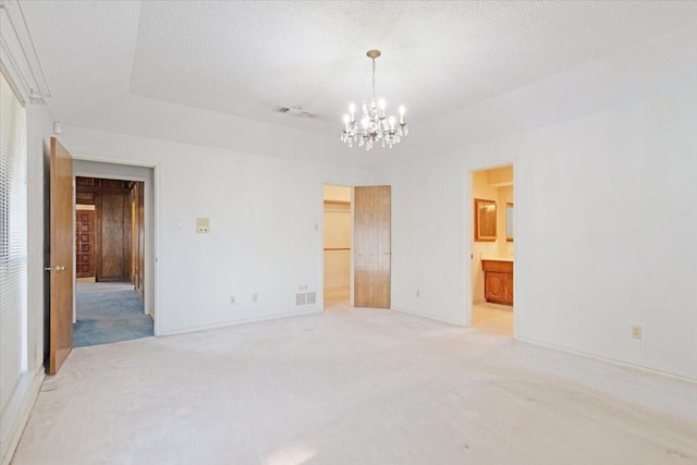 carpeted spare room featuring a chandelier and a textured ceiling