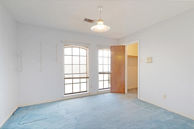 carpeted empty room featuring a textured ceiling