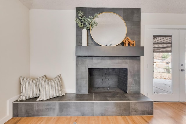 room details featuring wood-type flooring, a textured ceiling, and a tiled fireplace