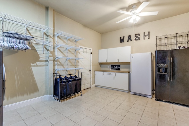 kitchen with black fridge with ice dispenser, white refrigerator, light tile patterned floors, and white cabinets