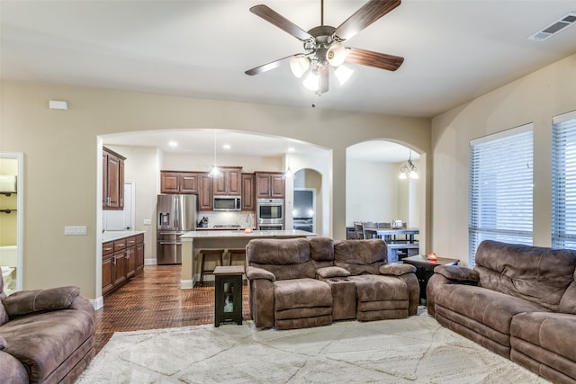 living room featuring ceiling fan with notable chandelier and hardwood / wood-style flooring