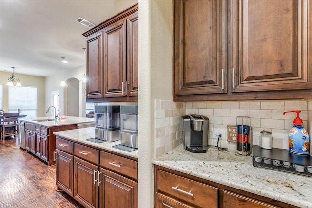 kitchen with sink, dishwasher, backsplash, pendant lighting, and a notable chandelier