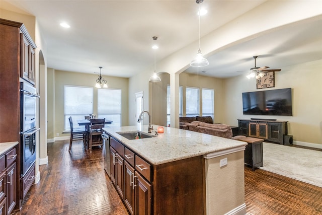 kitchen with ceiling fan with notable chandelier, a kitchen island with sink, hanging light fixtures, and sink