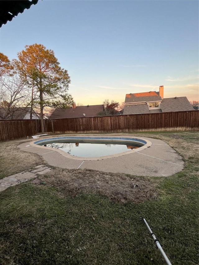 pool at dusk featuring a lawn