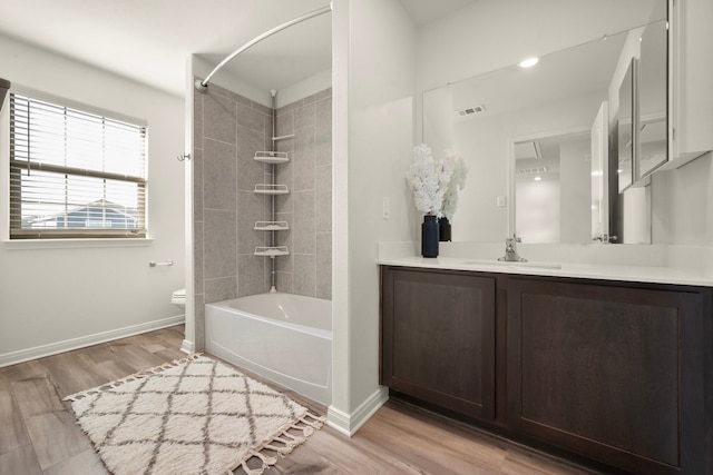 full bathroom featuring hardwood / wood-style floors, vanity, toilet, and tiled shower / bath