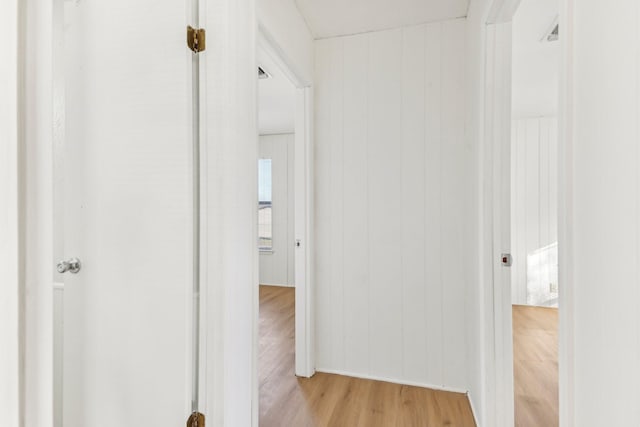 hall with wooden walls and light hardwood / wood-style floors