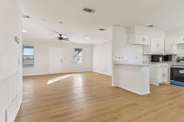 kitchen featuring white cabinets, ceiling fan, light hardwood / wood-style floors, stainless steel range with electric stovetop, and crown molding