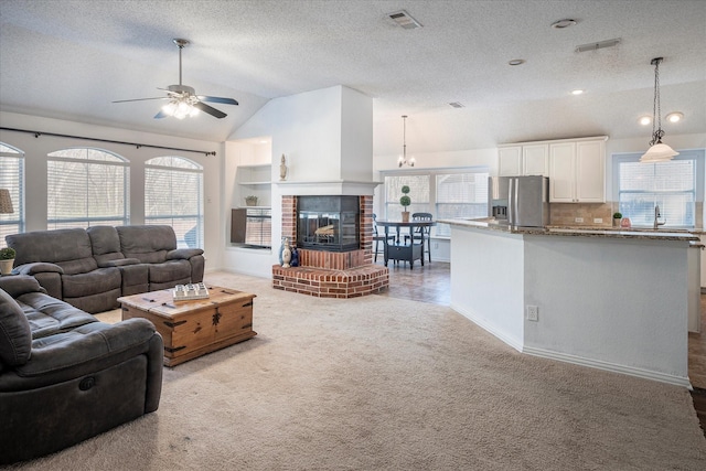 carpeted living room with a wealth of natural light, a brick fireplace, ceiling fan, and lofted ceiling