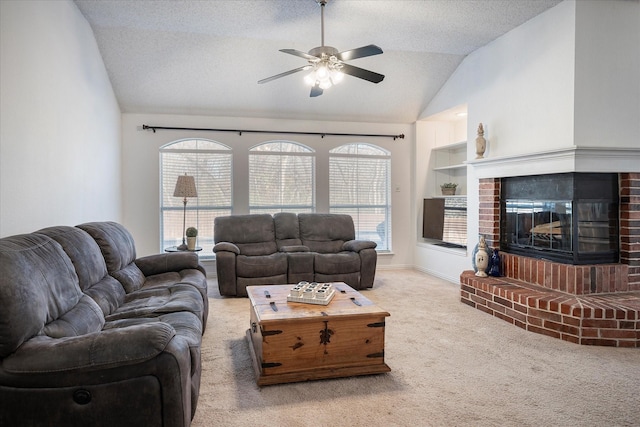 carpeted living room featuring a textured ceiling, ceiling fan, vaulted ceiling, and a brick fireplace