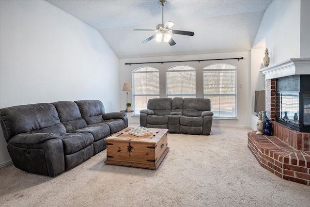 living room with carpet, lofted ceiling, ceiling fan, a fireplace, and a textured ceiling