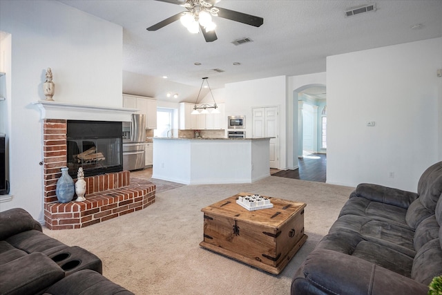 carpeted living room featuring ceiling fan and a fireplace