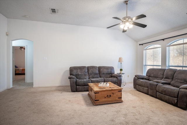 carpeted living room with a textured ceiling, ceiling fan, and vaulted ceiling