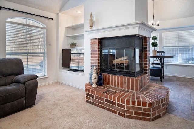 carpeted living room featuring a textured ceiling, a chandelier, lofted ceiling, and a brick fireplace