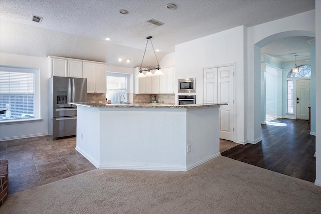 kitchen with pendant lighting, a center island, dark colored carpet, white cabinetry, and stainless steel appliances