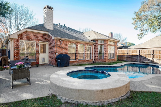 view of swimming pool with an in ground hot tub, grilling area, and a patio area